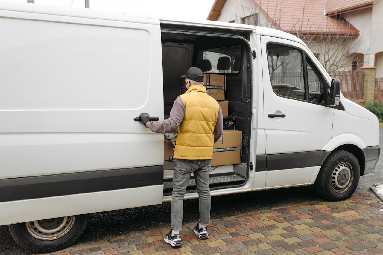 about-02 A delivery driver loads packages into a white van on a residential street.
